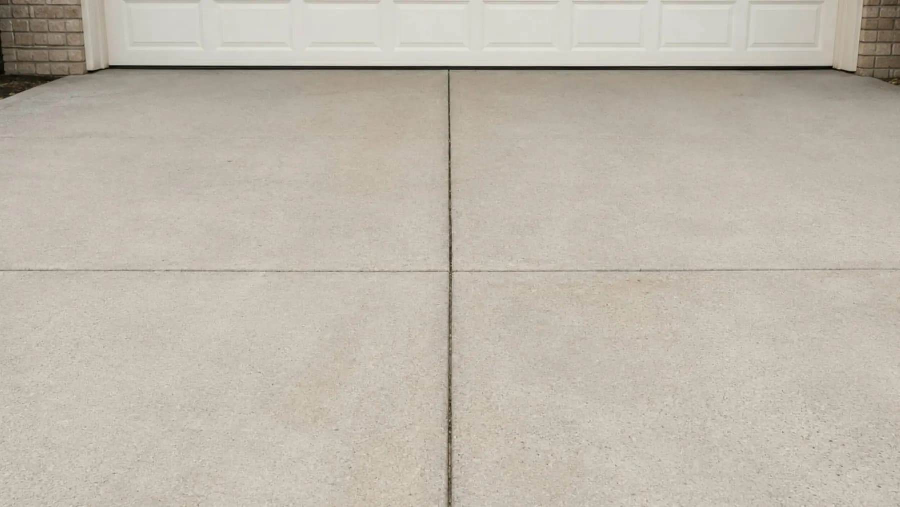 Concrete driveway with cut control joints in front of a garage door