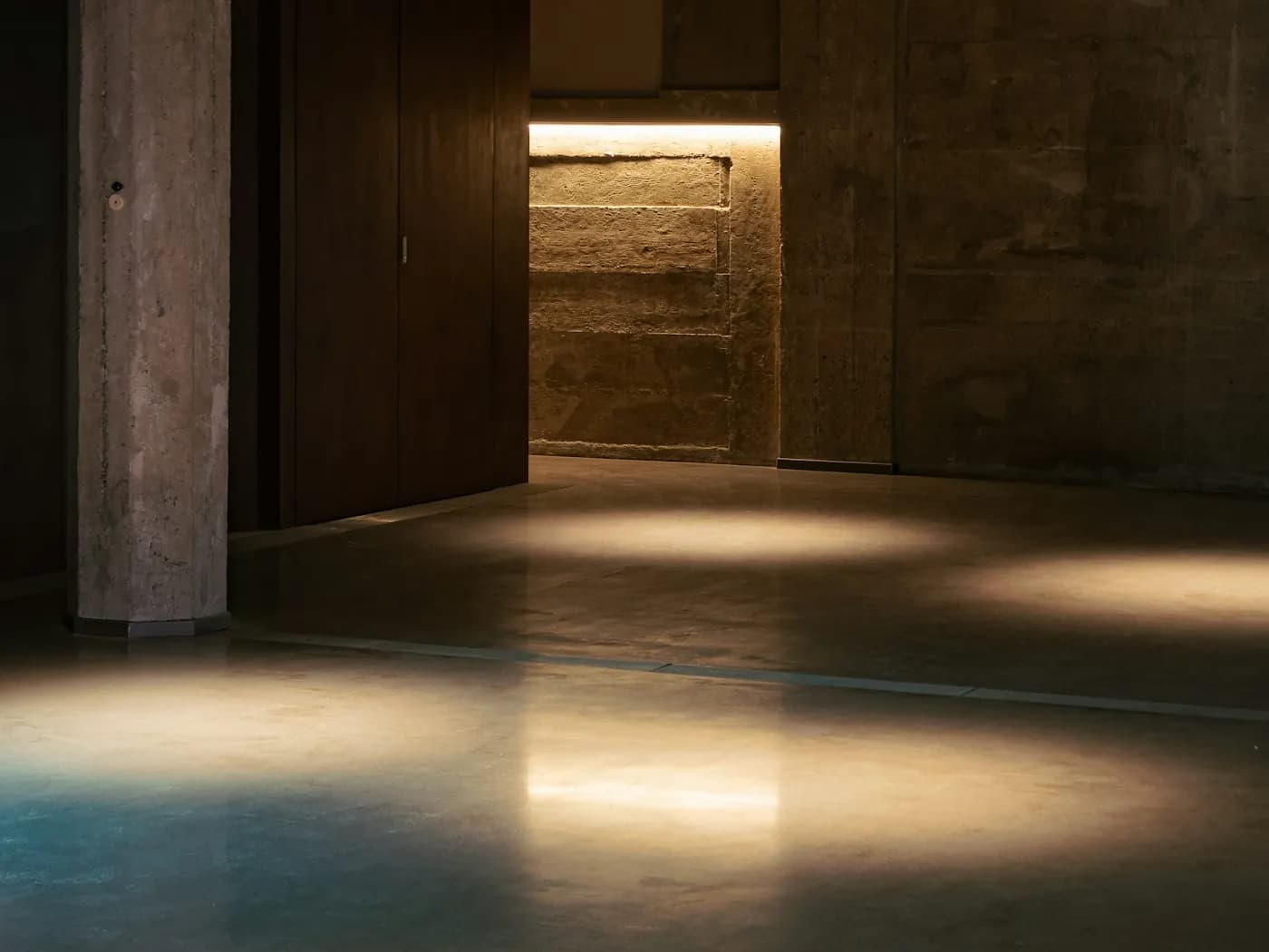 Empty concrete room lit through an open doorway