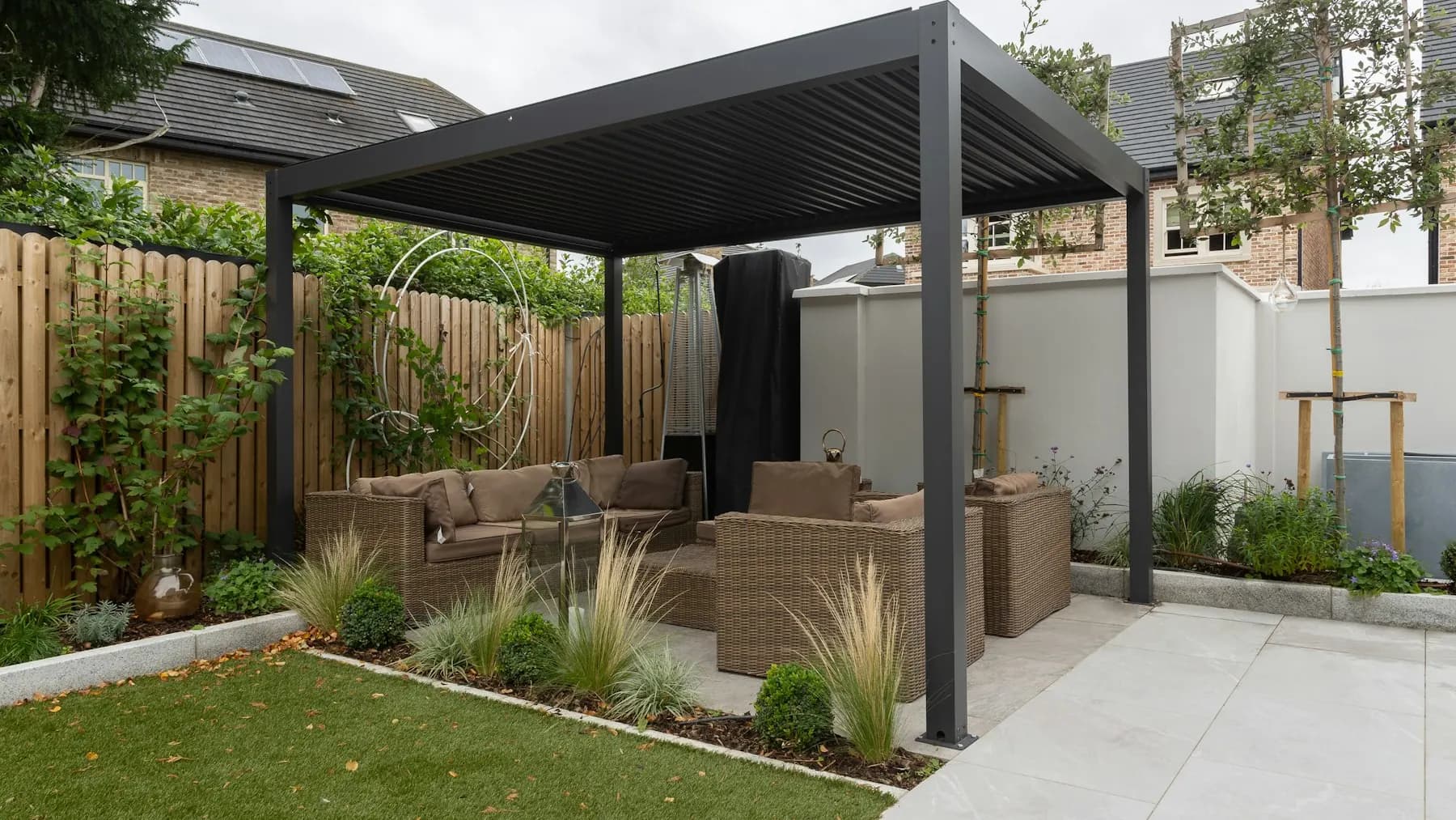 Backyard patio with a pergola and seating on a paved surface