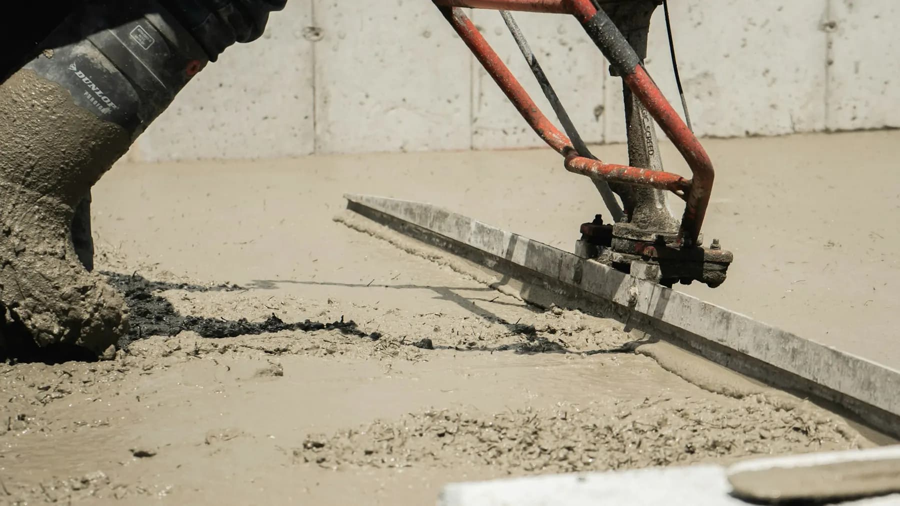 Power screed levelling fresh concrete on an active job site
