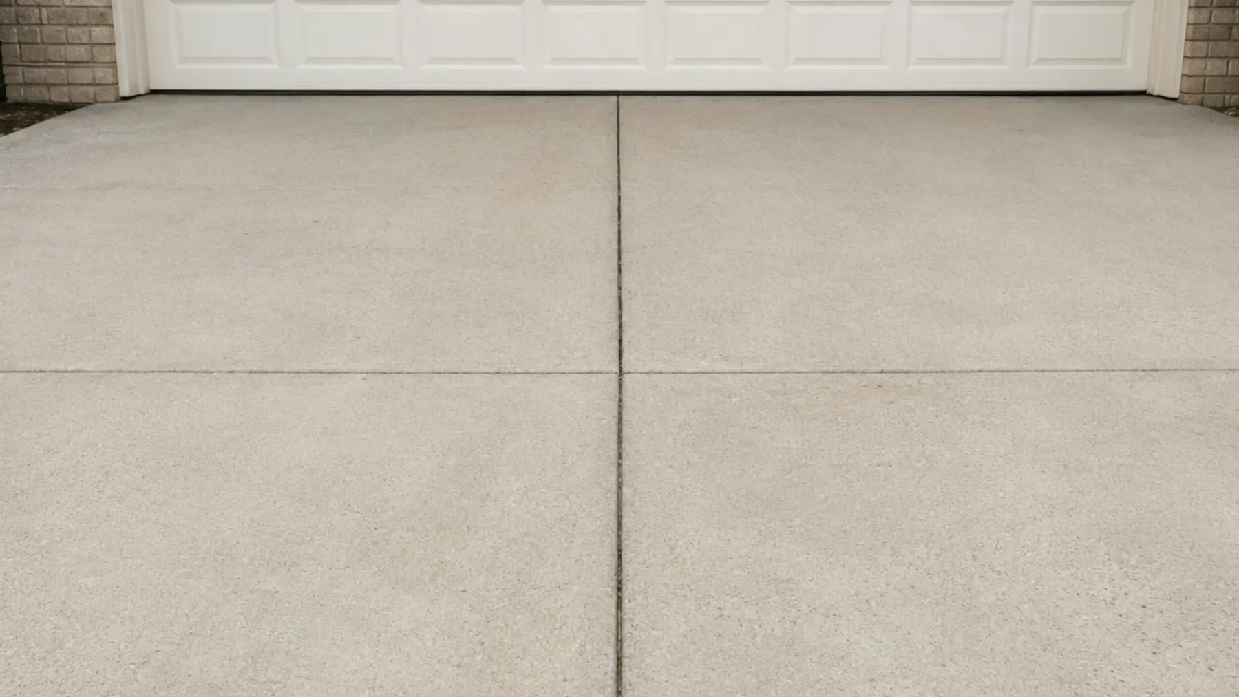 Concrete driveway with cut control joints in front of a garage door