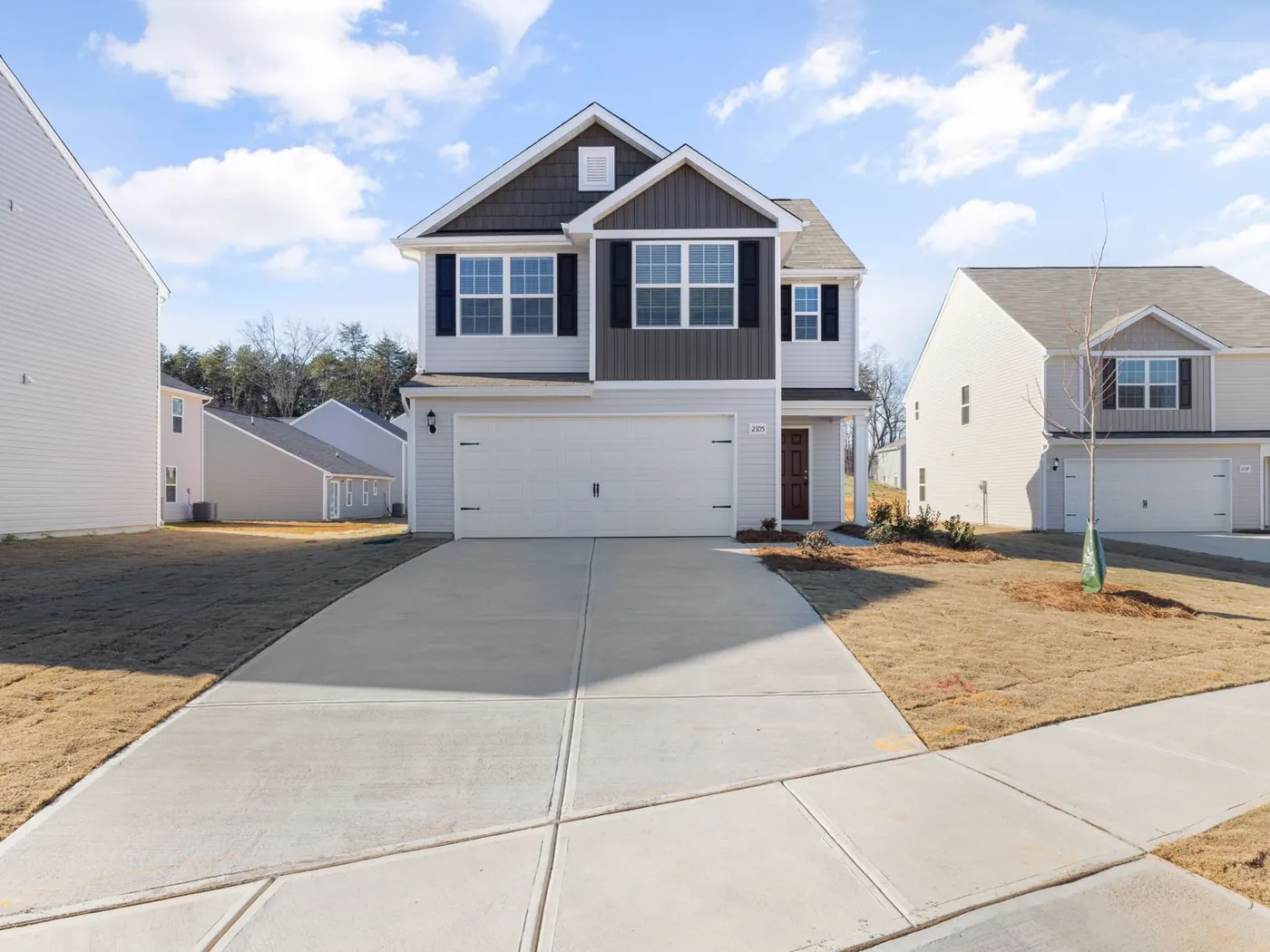 Newly poured concrete driveway with saw-cut joints in front of a new build