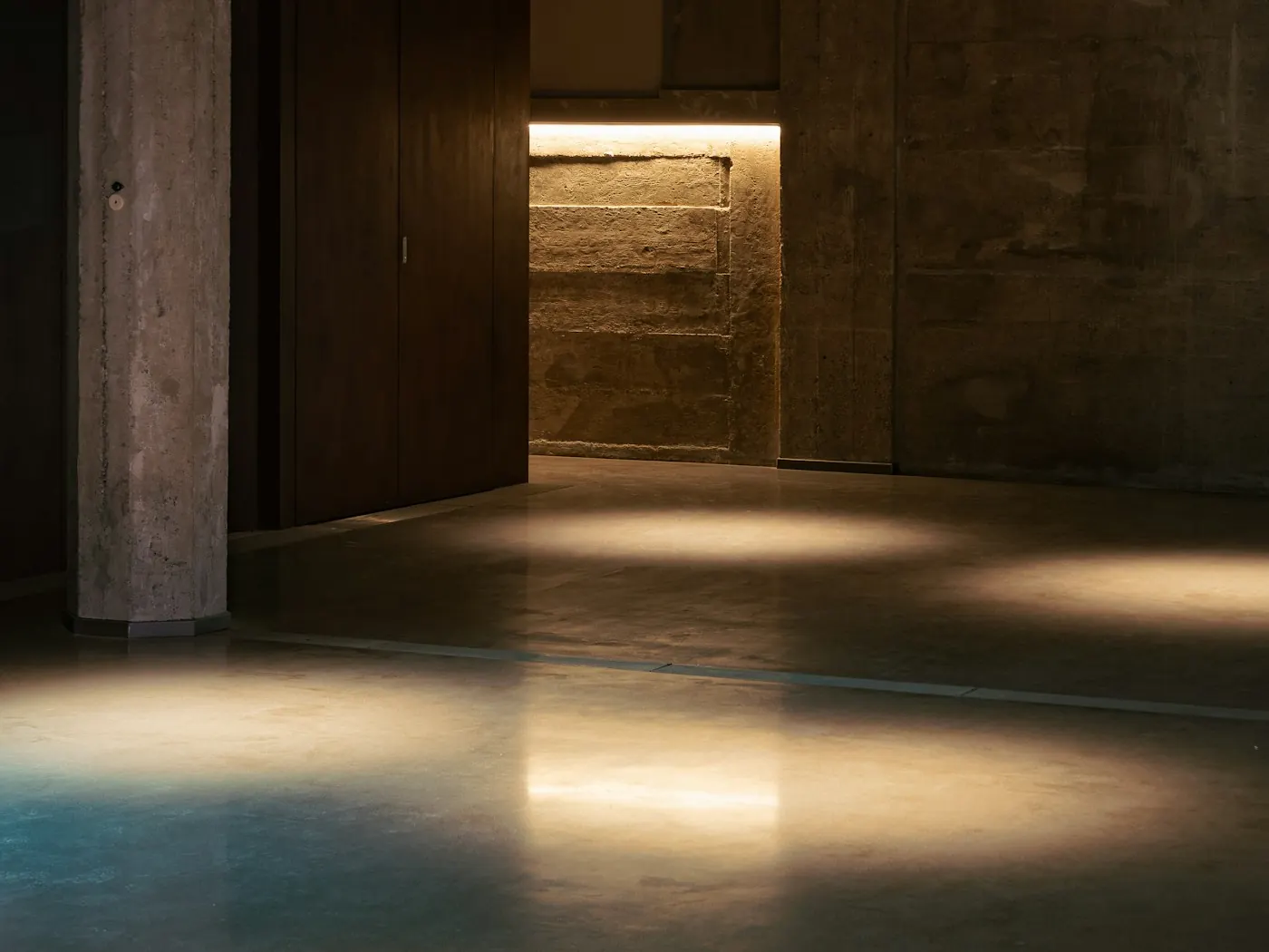 Empty concrete room lit through an open doorway
