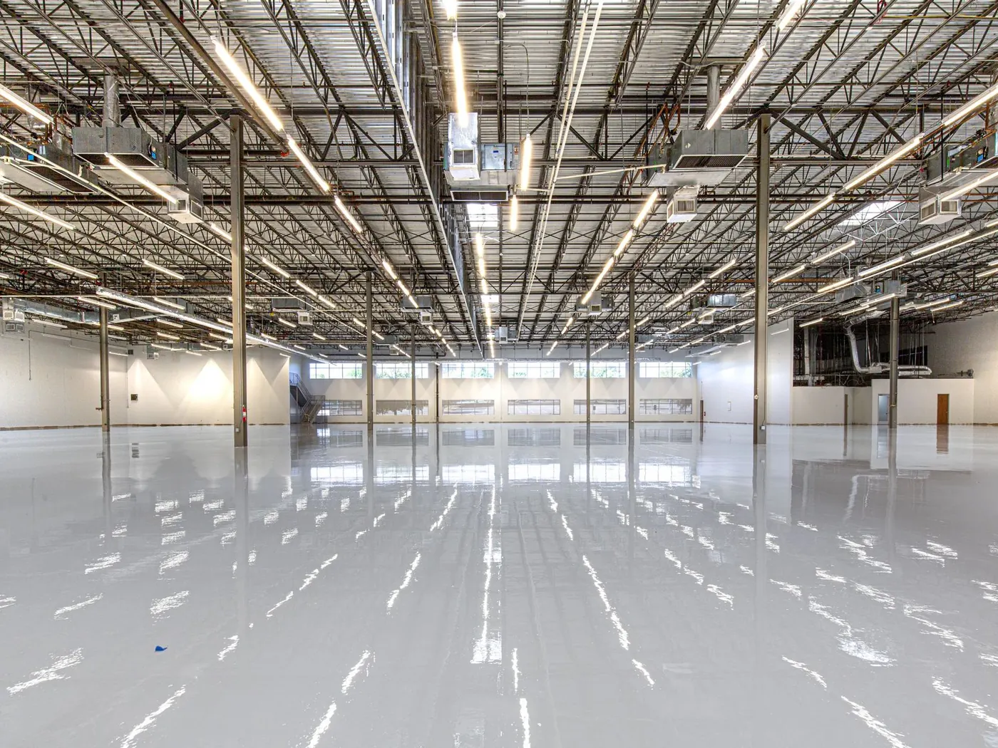 Empty warehouse with a polished concrete floor under strip lighting