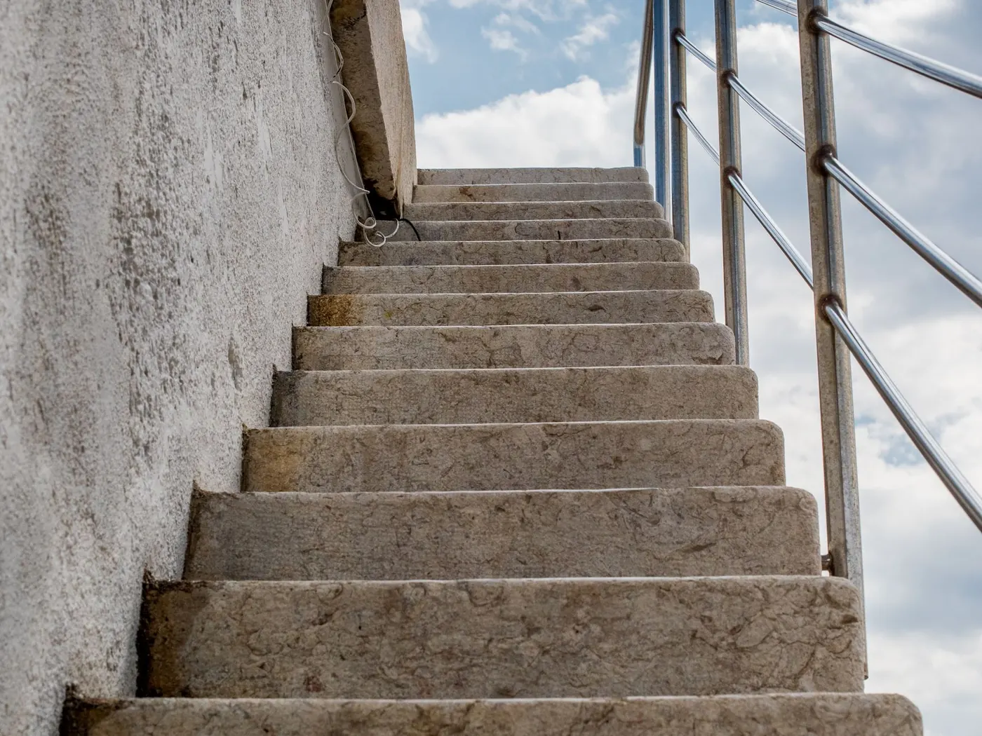 Flight of concrete stairs with a metal handrail against a wall