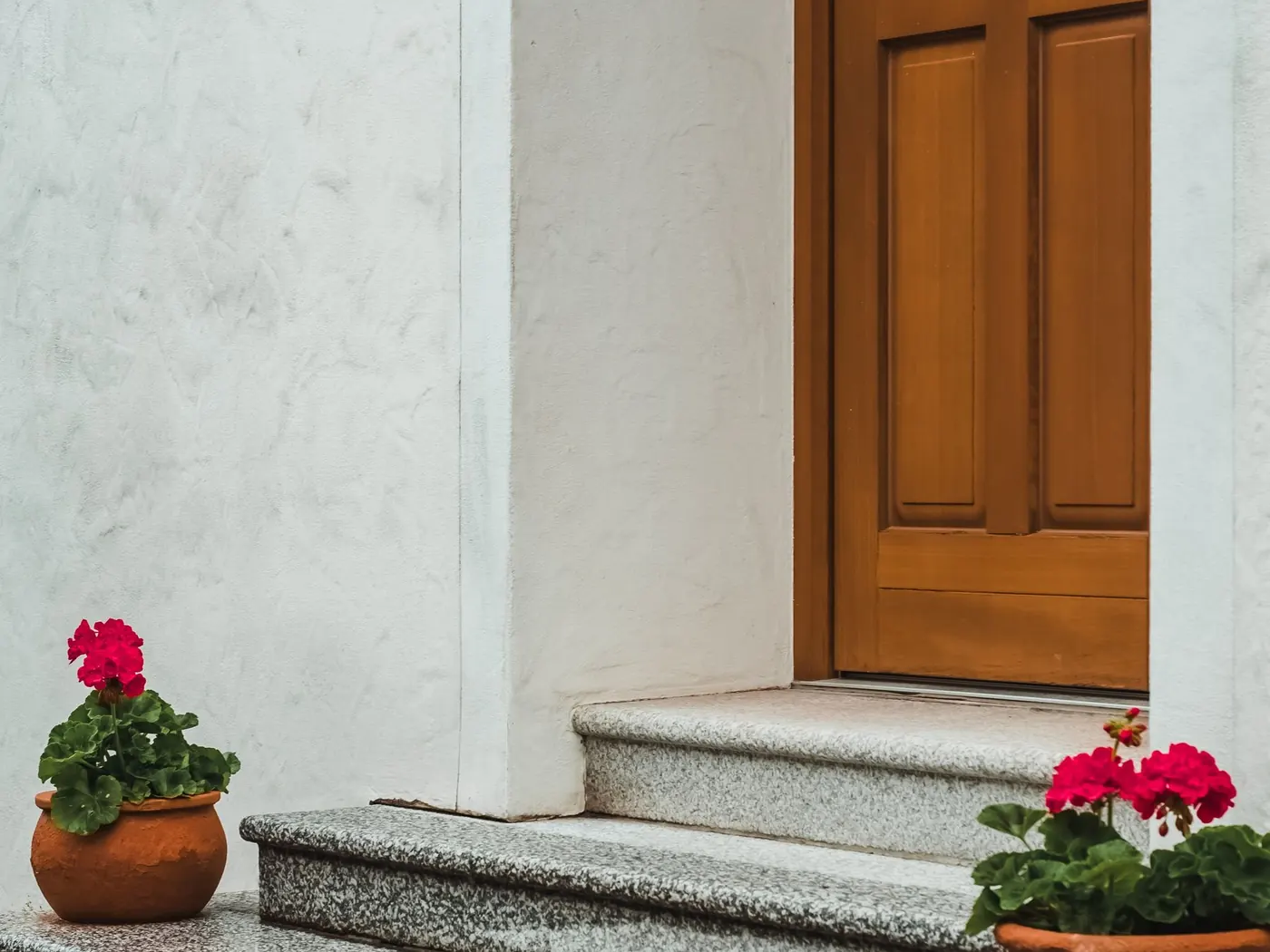 Concrete entry steps at a front door with potted flowers